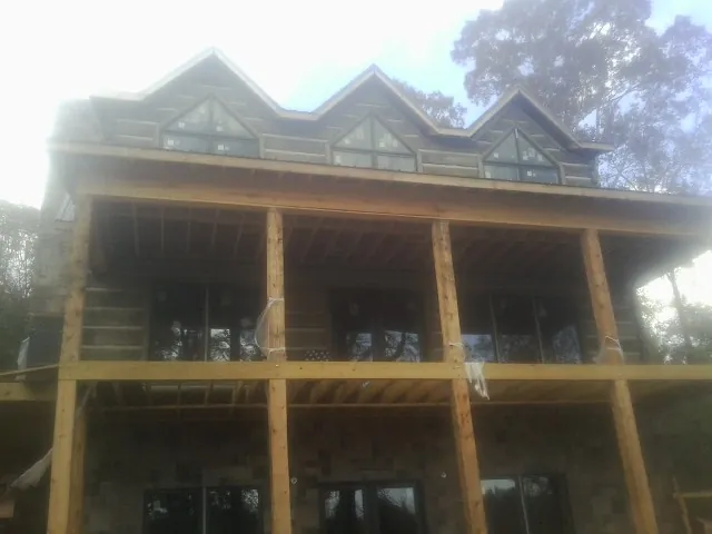 Dormers and porch framing on a large log home under construction — Roof Coating work by our crew in Gaston
